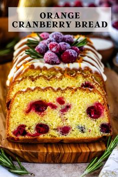 an orange cranberry bread on a cutting board with fresh berries and icing