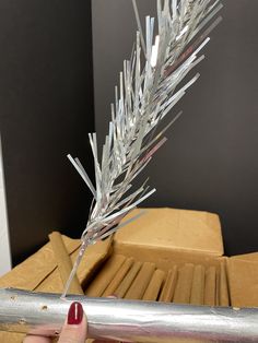 a hand holding a metal object with some tinsel on it