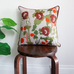 a pillow sitting on top of a wooden stool next to a plant