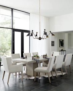 a dining room table with white chairs and a chandelier hanging from the ceiling