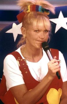 a woman holding a microphone in front of an american flag with stars on the background