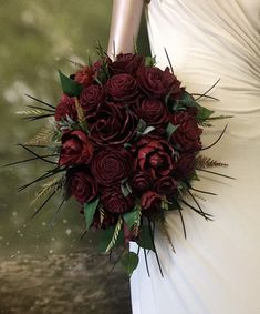 a bride holding a bouquet of red roses