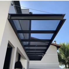 an outdoor covered patio area with glass walls and black metal roofing on the side of a house