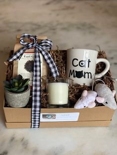 a gift box with a candle, coffee mug and other items in it on a table