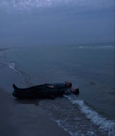 a man laying on top of a body of water next to the ocean under a cloudy sky