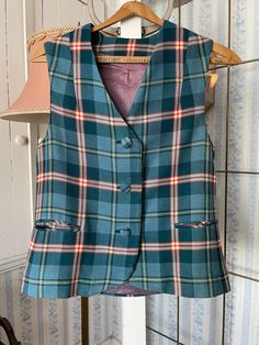 This beautiful wool blend vest was made by Bernard Casuals in Vancouver, in green, blue, red, yellow, beige and black plaid. It has the original cloth covered buttons in the front, two front pockets (that haven't been unstitched yet), and it is fully lined. Marked size 10. The measurements, taken with the vest lying flat, are: shoulder to shoulder, 14 inches; armpit to armpit, 17 1/2 inches; length, 21 inches in front and 22 1/2 inches in back; bottom edge, 18 1/2 inches. There is a small hole in the lining in the centre back; otherwise, the vest is in very good condition. See Vintage Pants & Skirts, item B547, for matching skirt/kilt! Plaid Vest For Fall, Plaid Sleeveless Vest For Fall, Classic Plaid Vest For Fall, Fitted Plaid Vest For Winter, Classic Plaid Vest, Classic Plaid Sleeveless Vest, Classic Sleeveless Plaid Vest, Fitted Plaid Sleeveless Vest, Plaid Sleeveless Vest For Work