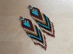 two pairs of beaded earrings sitting on top of a wooden table