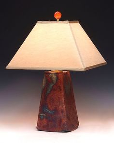 a lamp that is sitting on top of a wooden base with a white shade over it