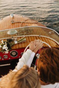 two people sitting on a boat in the water with their hands on the steering wheel