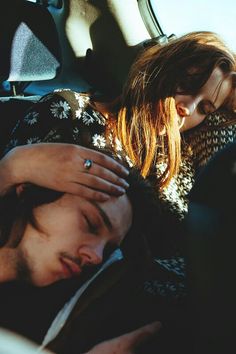 a man and woman sleeping in the back seat of a car