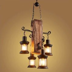 an old fashioned light fixture hanging from a chain with three lights on it and a wooden block in the background