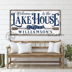 a wooden bench sitting in front of a wall with a sign that says welcome to the lake house