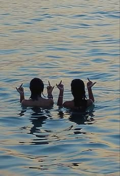 two people in the water making peace signs