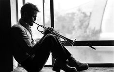 a man sitting on top of a window sill holding a trumpet