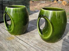 two green mugs sitting on top of a wooden table