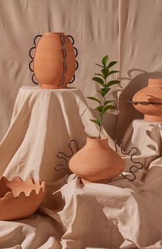 three wooden vases sitting next to each other on a cloth covered table with a plant in the middle