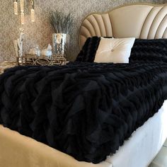 a large black blanket sitting on top of a bed next to a night stand with candles