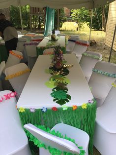 tables and chairs covered in grass under a tent