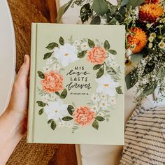 a person holding up a book with flowers on it and the words love last forever