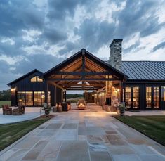 a large house with a covered walkway leading to the front door and patio area at dusk