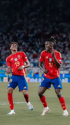 two soccer players in red and blue uniforms are on the field with their hands together