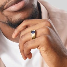 a close up of a person wearing a gold ring with a blue stone on it