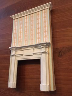 an old fashioned fireplace with striped wallpaper on the top and bottom part, next to a wooden floor