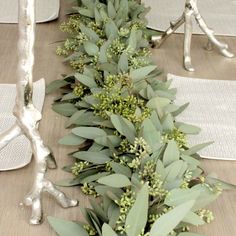 the table is set with silverware and greenery