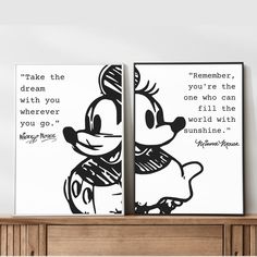 two mickey mouse paintings on top of a wooden dresser next to a wall with a quote