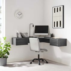 a corner desk with a computer on it next to a potted plant and clock