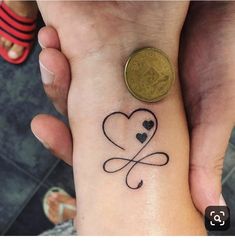 two people holding hands with tattoos on their wrists and one has a coin in the other hand