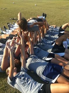 a group of young people laying on top of each other in a circle with their hands together