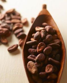 a wooden spoon filled with coffee beans on top of a table