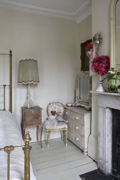 a bedroom with a bed, dresser and mirror in the corner next to a fire place