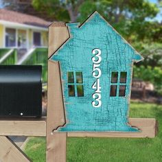 a blue house shaped mailbox sitting on top of a wooden bench