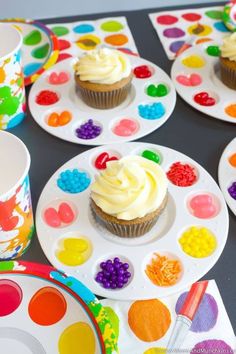 cupcakes with white frosting on colorful plates and paint splattered napkins