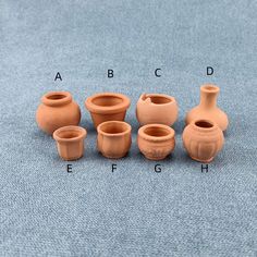 six clay vases are shown on a blue surface with the letters abc, c, d, e, f and h