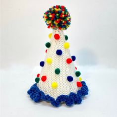 a white knitted christmas tree with multi colored pom poms on it's top