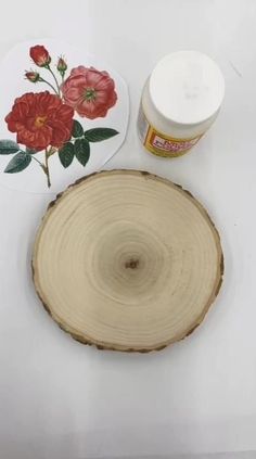 a piece of wood that has some flowers on it and a jar of paint next to it