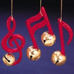 three ornaments hanging from strings with musical notes and bells attached to them, on a blue background