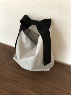 a white bag with a black bow on the top is sitting on a wooden floor