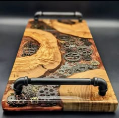 a wooden cutting board with black handles and gears painted on it's sides, sitting on a table