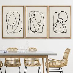 three abstract paintings hang on the wall above a dining room table with wicker chairs