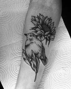 a black and white photo of a sunflower with a bird on it's arm