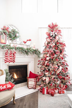 a decorated christmas tree sitting in front of a fire place with stockings on the mantle