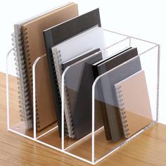 a stack of notebooks in a clear holder on a wooden table with a white background