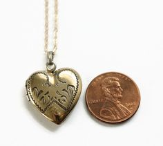 Vintage Heart Locket Necklace. This gold filled locket has decorative engravings and the letter P at the bottom. On the back, it is engraved with the date 8-19-5. Inside the locket contains one metal frame. The locket opens and closes easily and securely. The new gold filled chain was added by me, not vintage. Circa 1950's No hallmarks Measurements- Chain is 18 inches in length Locket is about 1 inch length Very good condition. Minor wear due to age and use. Collectible Gold Jewelry With Heart Charm, Valentine's Day Engraved Medallion Jewelry, Vintage Jewelry For Valentine's Day Wedding, Heirloom Engraved Locket Necklace For Valentine's Day, Vintage Jewelry For Wedding On Valentine's Day, Vintage Wedding Jewelry For Valentine's Day, Vintage Filigree Heart Pendant Jewelry, Vintage Etched Heart Pendant Jewelry, Antique Stamped Necklace Gift