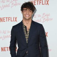 a smiling young man in a suit and plaid shirt at the netflix upfront event