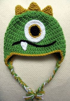 a crocheted green hat with an eyeball on the front and a bow tie around the brim