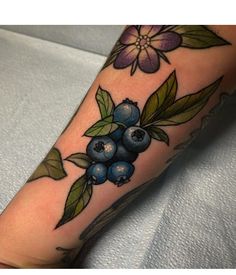 a tattoo with blueberries and leaves on it